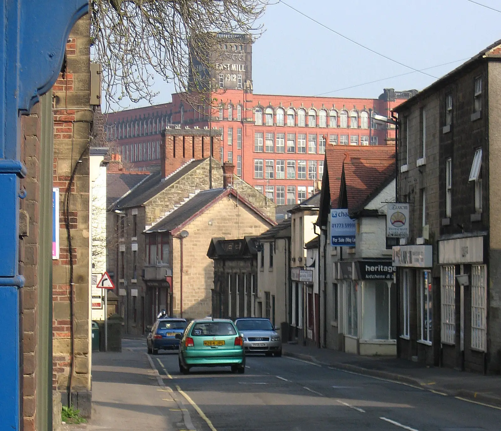 The East Mill rising above the stone cottages of Bridge Street, Belper, its tower lettered ‘East Mill 1912’.
